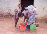  46. Mother doing laundry while her baby sleeps on her back